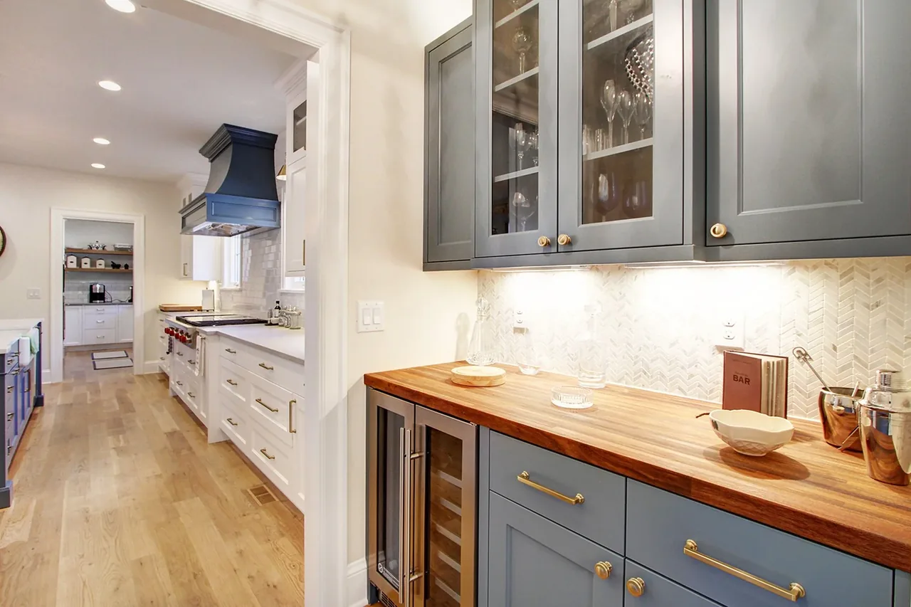 Kitchen featuring blue and white cabinets, wood countertops, and a patterned tile backsplash in the French Country Denver Wash Park project.