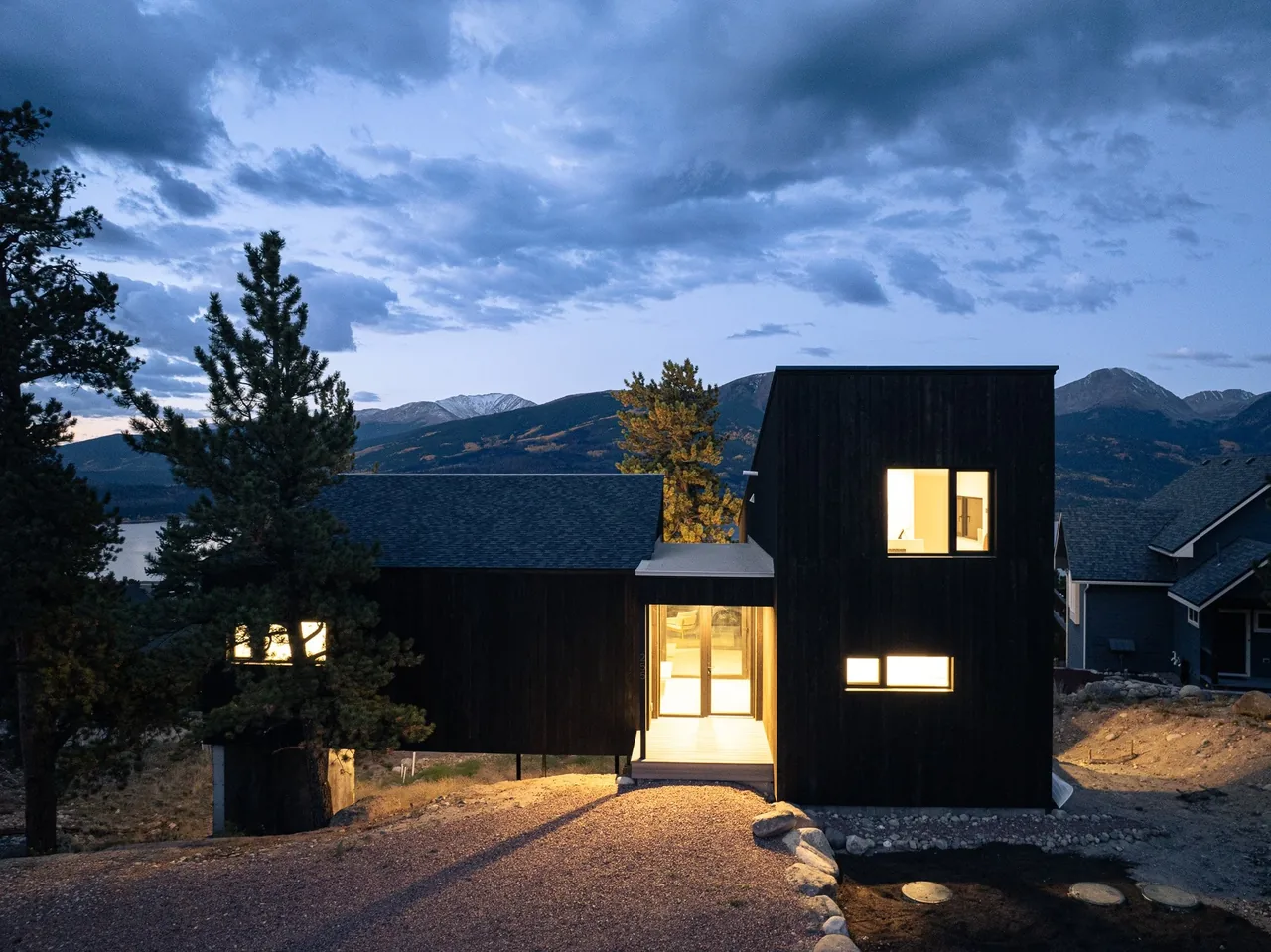 Twin Lakes Bothy is a modern house with black wood siding set on a hilltop with mountain views.