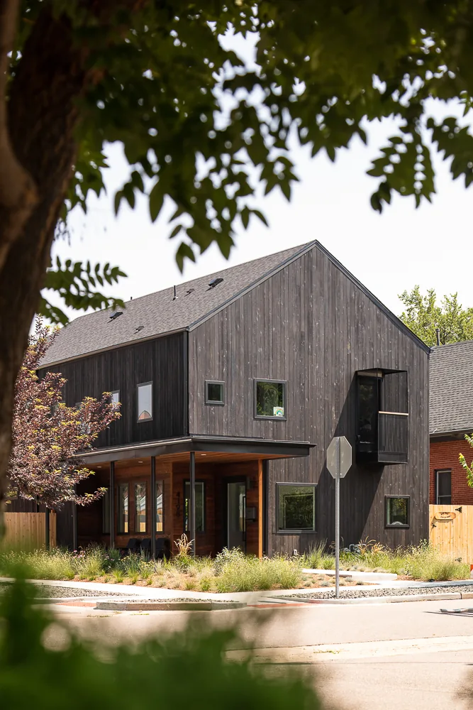 The 43rd Residence features a two-story design with dark vertical wood siding and a covered front porch framed by wood posts.