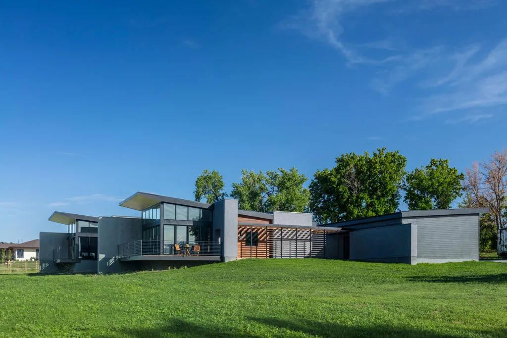 The Hoff Residence features flat roofs, large windows, balconies with metal railings, and a textured wall finish.