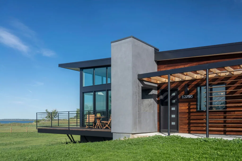 The Hoff Residence features a modern exterior with floor-to-ceiling glazing and a balcony with metal railings.