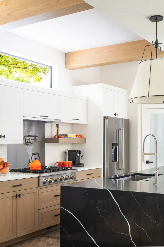 The kitchen features a black marble island, wood lower cabinets, white upper cabinets, and stainless steel appliances.