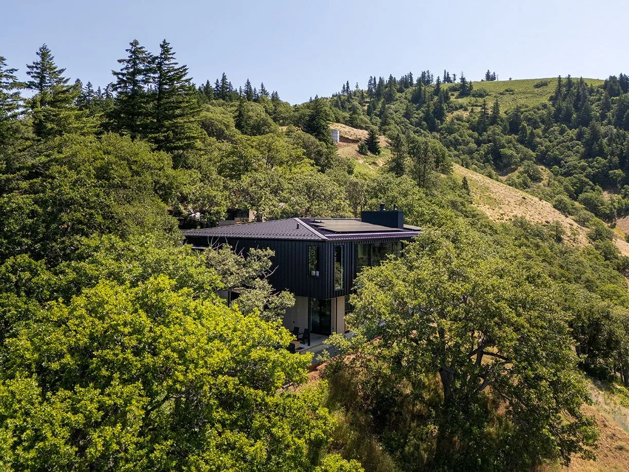 Hidden Oaks Residence by Centerfield Studio is a modern house with black cladding, nestled on a wooded hillside near Portland.