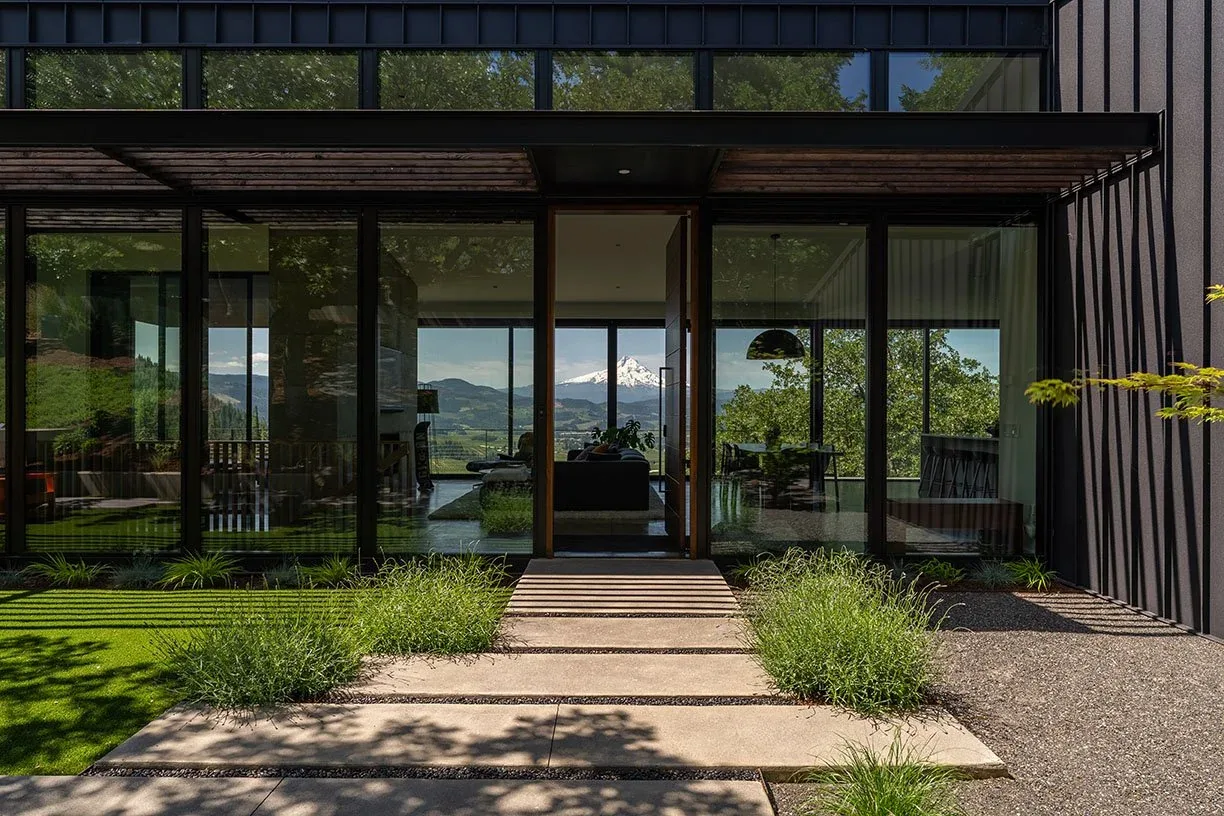 The Hidden Oaks Residence features floor-to-ceiling glazing and black cladding with a view of a snow-capped mountain.
