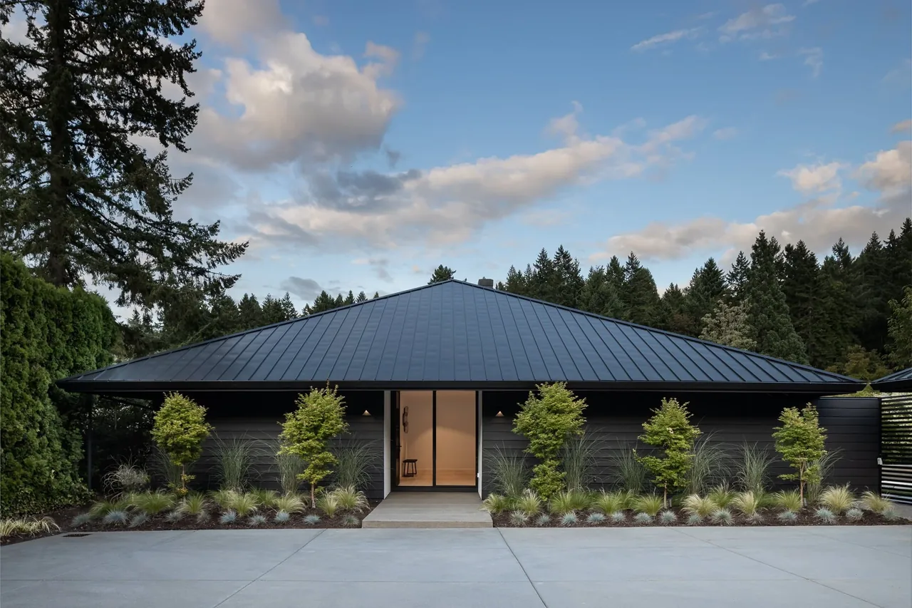 Cardinal house features a modern exterior with a standing seam metal gable roof and symmetrical plantings near the entry.