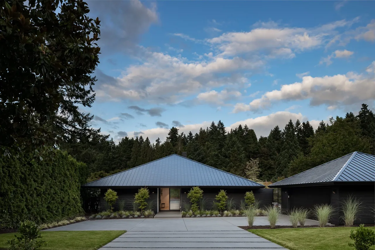 The cardinal house in Portland features a symmetrical facade with a metal roof and landscaped entrance.