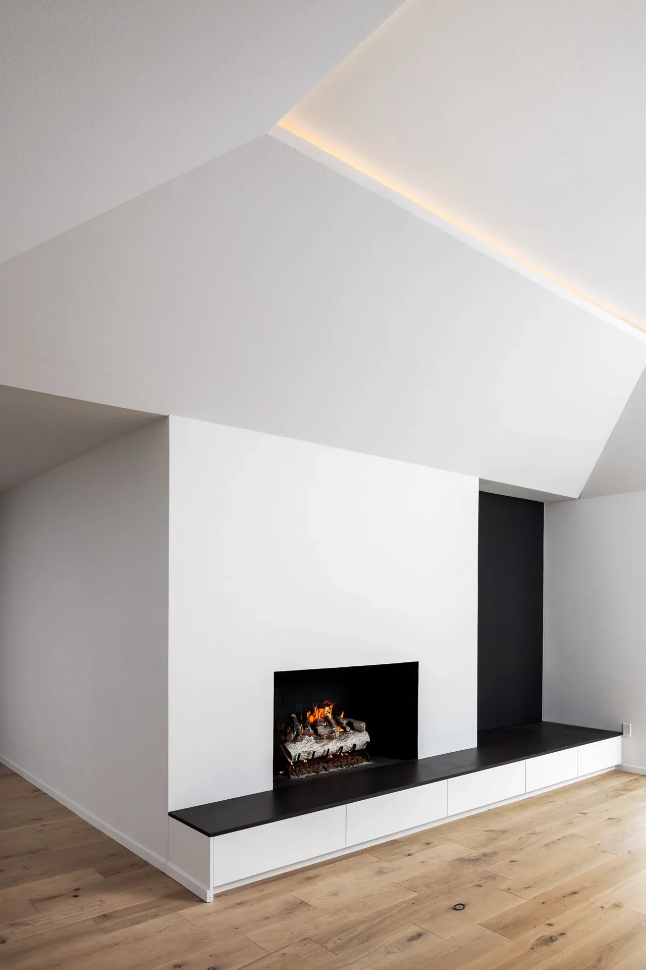 White wall with a black fireplace inset and a built-in bench with storage below.