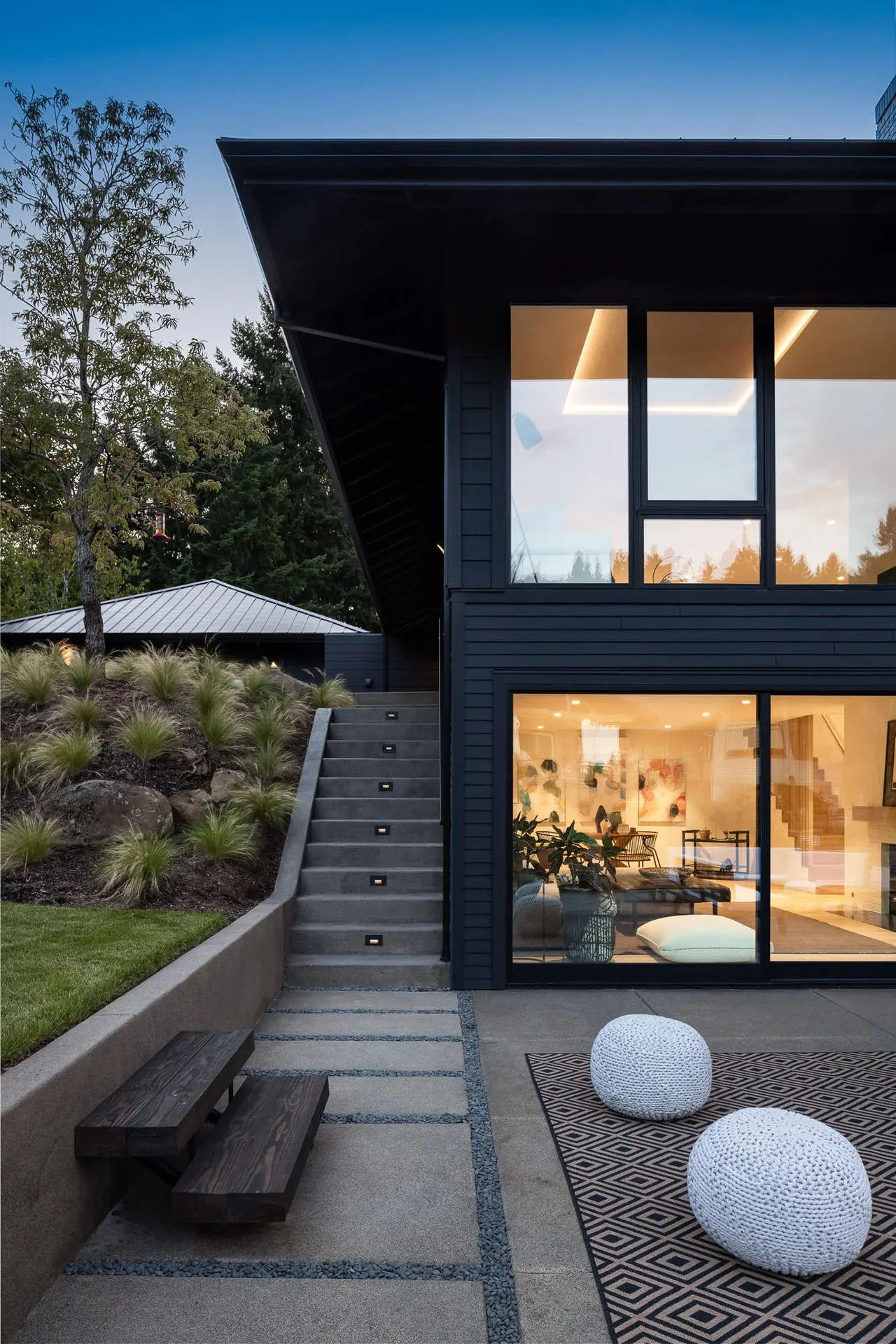 Cardinal House features an outdoor concrete patio seating area adjacent to its dark wood siding exterior with large glass windows.