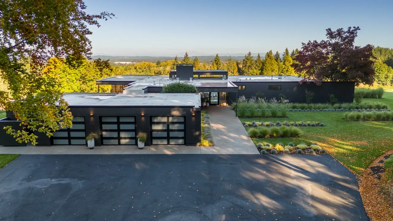 Burnt Tree Farm features a modern single-story house with a flat roof and black garage doors surrounded by manicured landscaping.