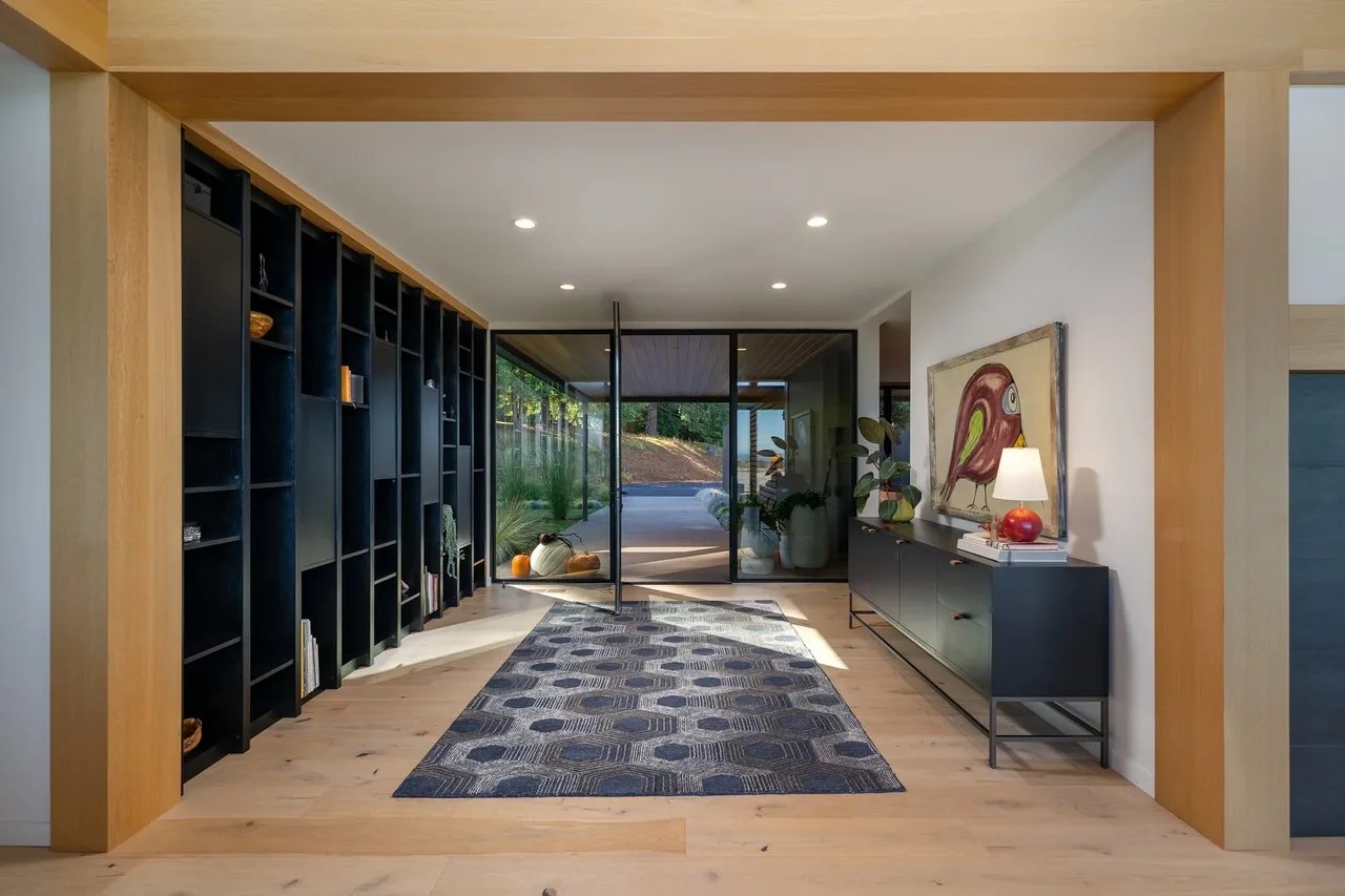Entry hallway features black built-in shelving and a black sideboard with decorative elements under wood framing.