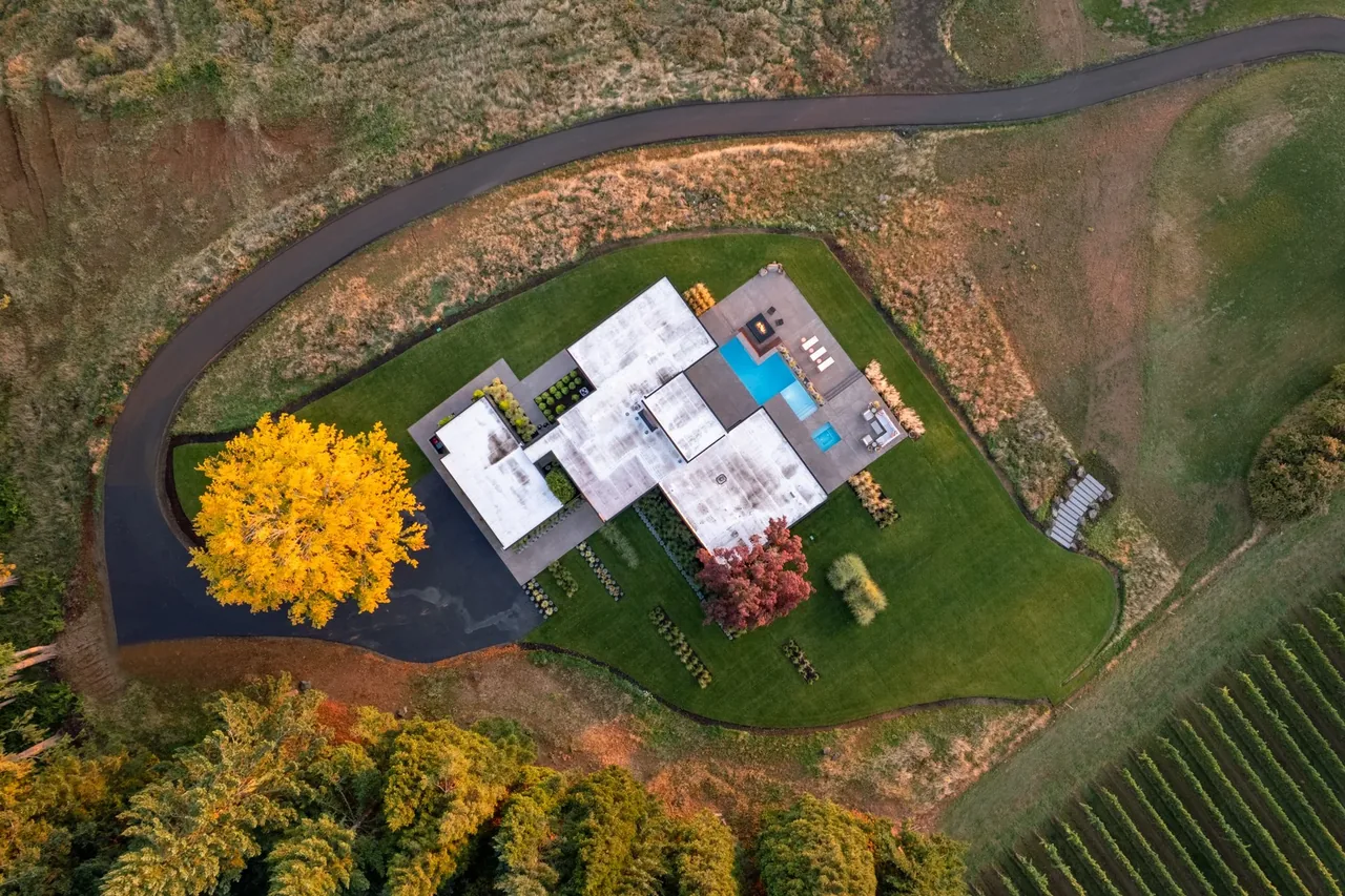 Burnt Tree Farm features a modern flat-roof building with a pool and outdoor seating on a landscaped plot.