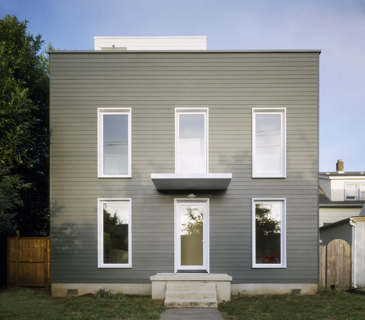 The Cape Cod project by Waechter Architecture features a modern box-shaped facade with symmetrical windows and a simple entrance canopy.