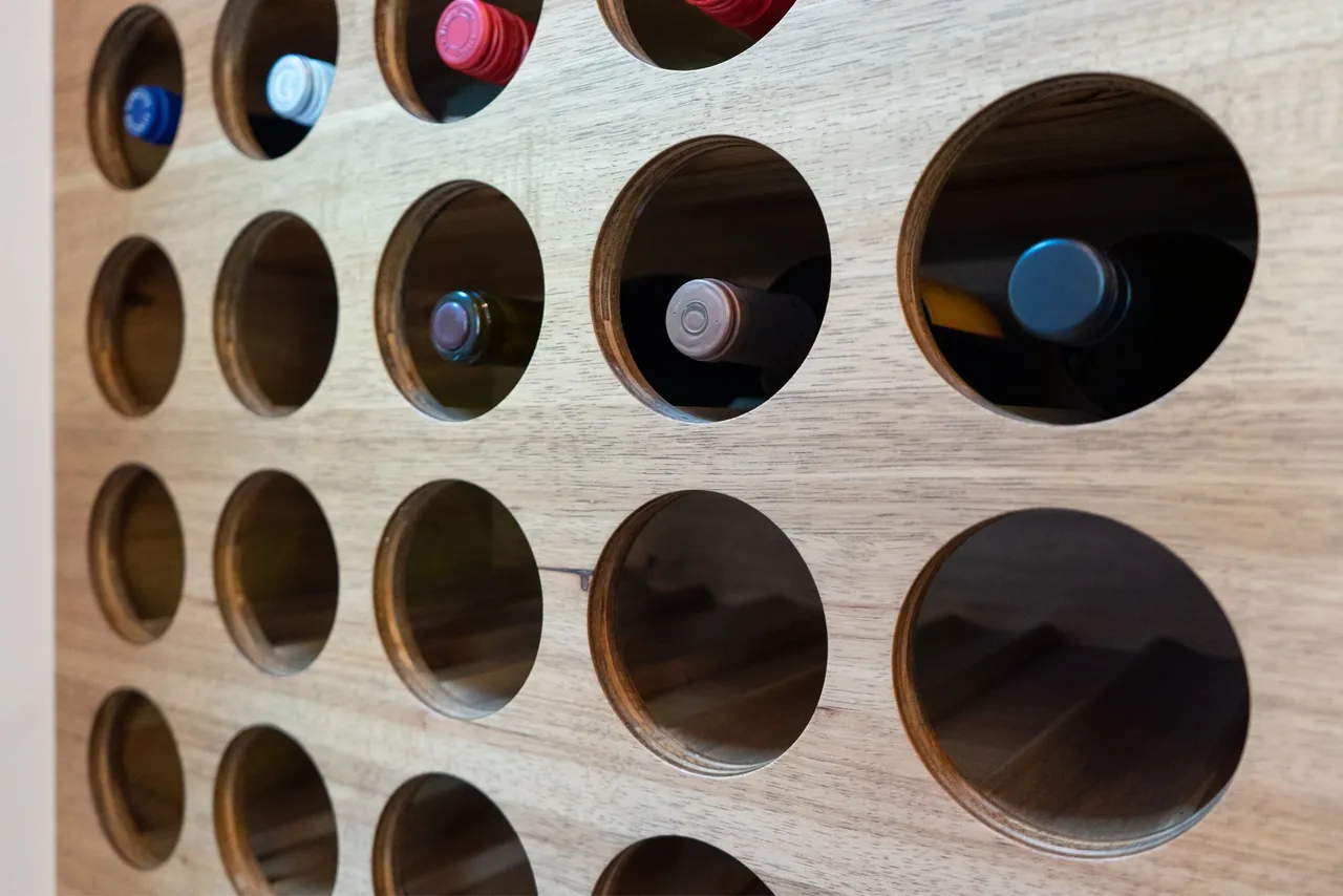 Wooden wine storage rack with circular openings holding bottles horizontally.