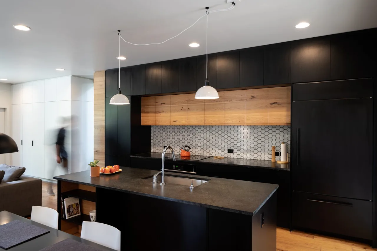 Kitchen in the Cleveland House by Grummer Architecture features black and wood cabinetry with hexagonal tile backsplash and a central island.