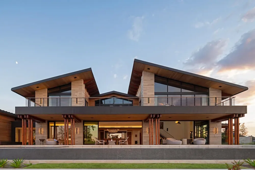 Pelican House features a modern exterior with wide roof overhangs, large glass windows, and an expansive covered patio area.