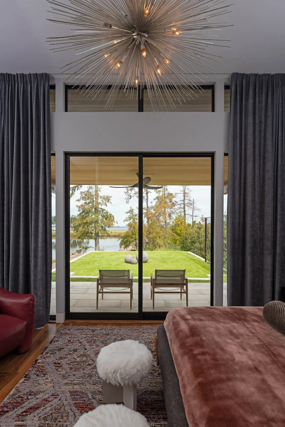 Bedroom with sliding glass doors looking out to a patio and waterfront lawn at Pelican House.
