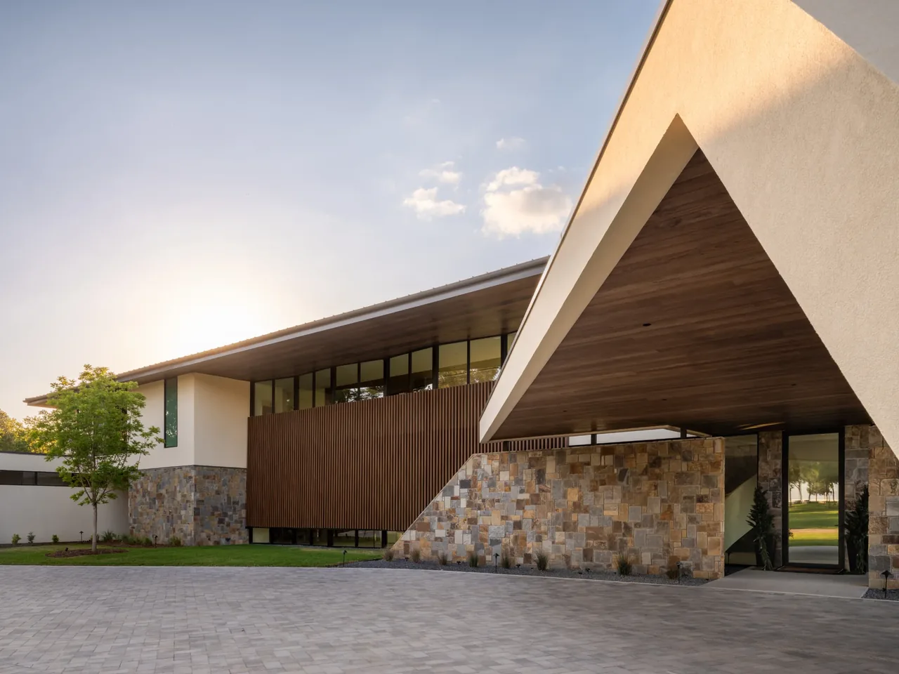 Exterior front of Horse Ranch home features stone walls, wood slat panels, and deep eaves with a flat roof.