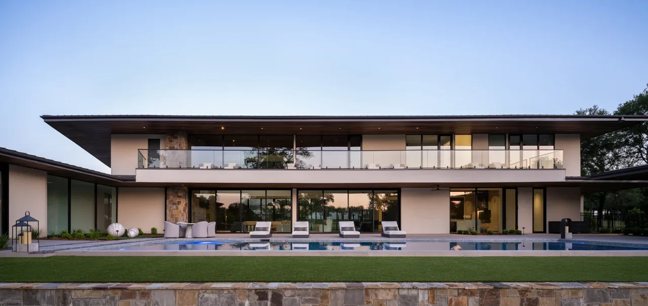 The Horse Ranch project features a modern two-story home with a flat roof and large exterior glazing overlooking a pool and lawn.