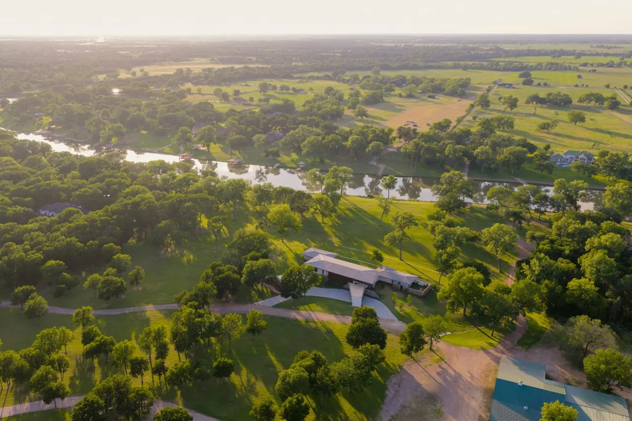 The Horse Ranch features a cantilevered entrance and large roof overhang situated beside a winding river.