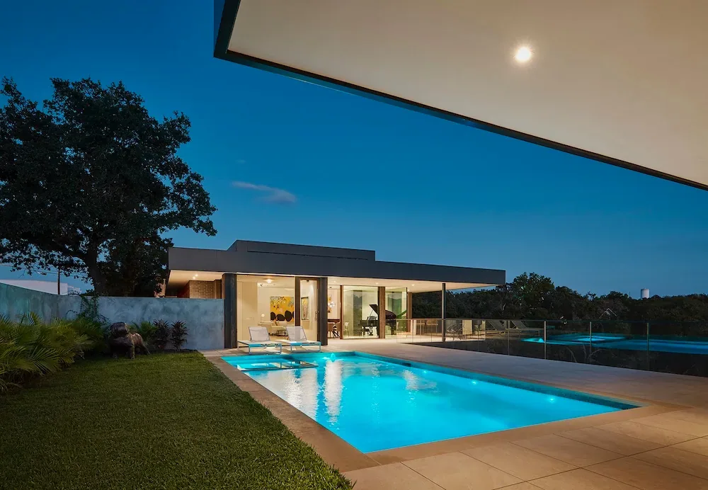 Villa Morada shows a modern exterior with a pool and glass railing at dusk.