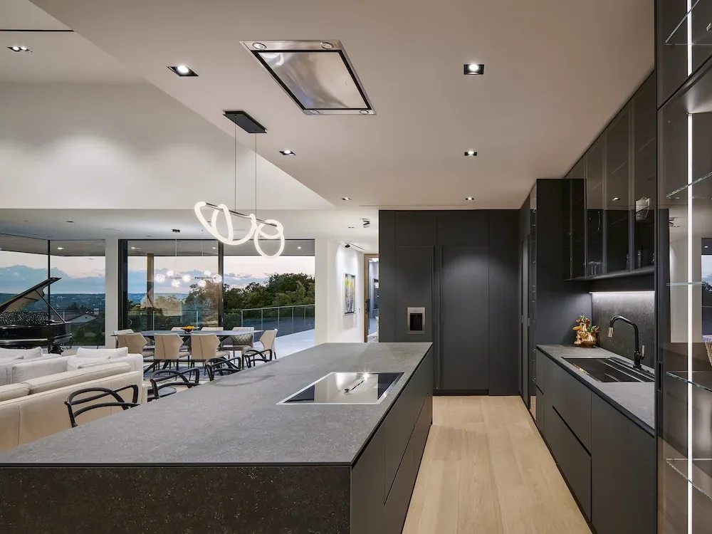 Villa Morada kitchen and living area featuring dark kitchen cabinets, kitchen island, and grand piano in the background.