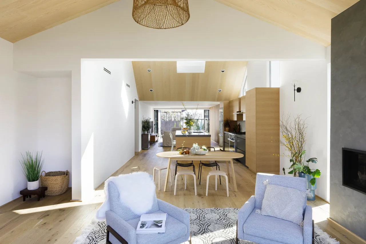 Open living, dining, and kitchen space with vaulted ceiling and wood finishes at Curson Residence by Nwankpa Design.