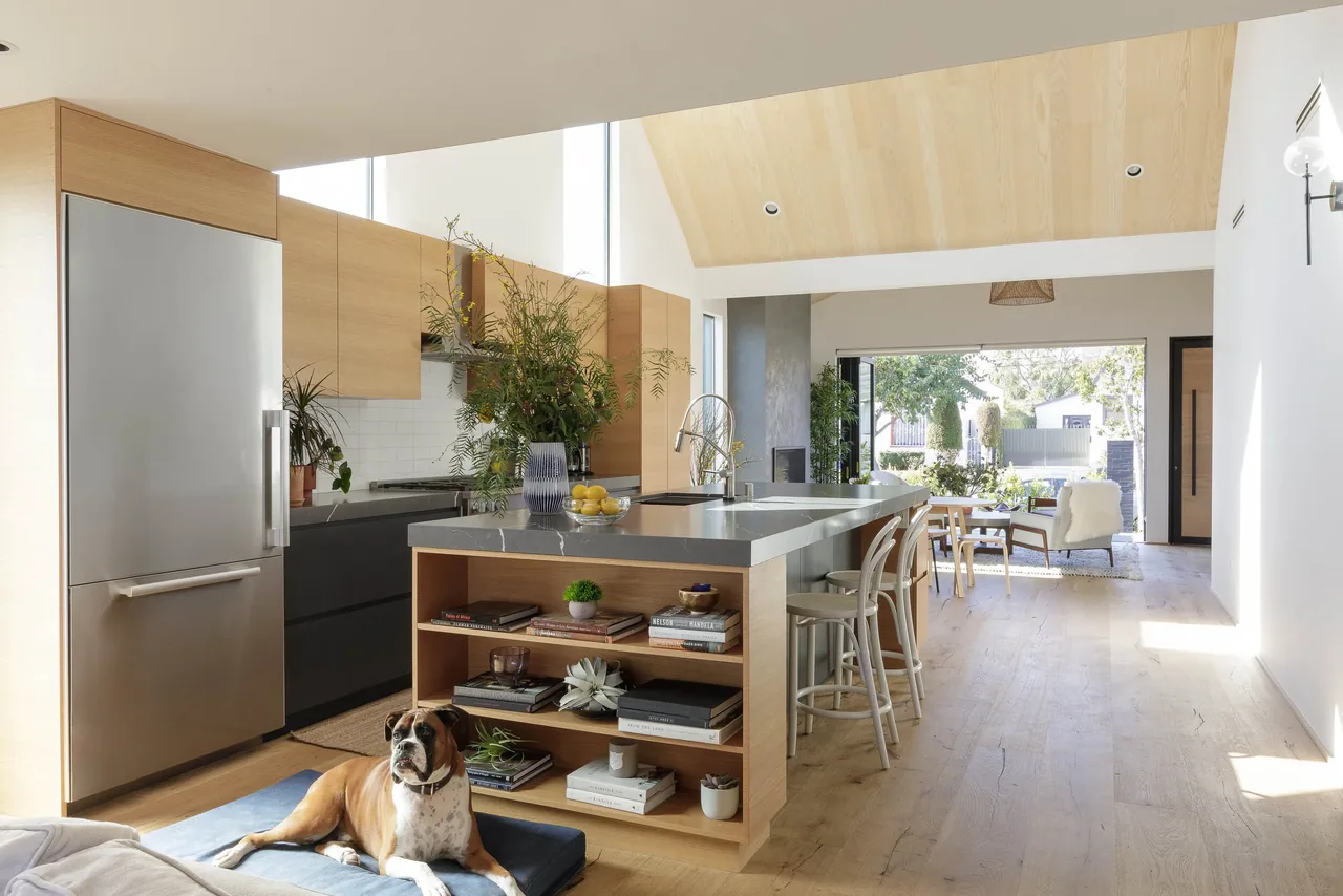 Curson Residence kitchen with wood-paneled ceiling, kitchen island seating, and a dog resting on the floor cushion.