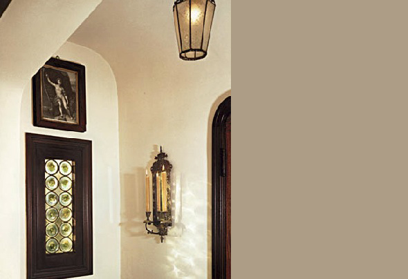 Wall featuring an arched doorway, a decorative candle sconce, and framed artwork above a textured glass window.
