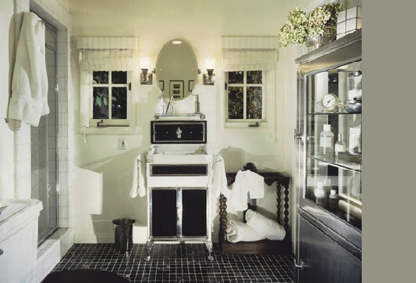 Bathroom featuring a black and white vanity with an oval mirror, flanked by two wall sconces and small windows.