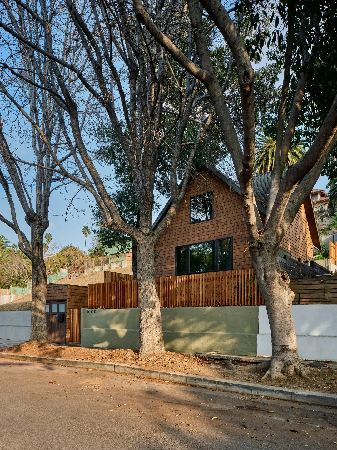 Silver Lake Treehouse features wood shingle siding and a pitched gable roof with black window frames.
