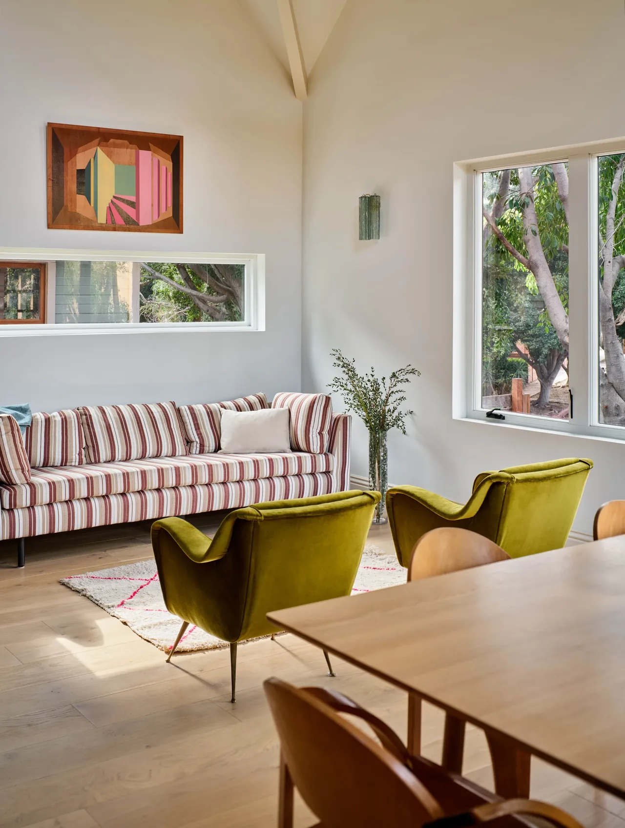 Silver Lake Treehouse living room features a striped sofa, green armchairs, and multiple large windows with tree views.