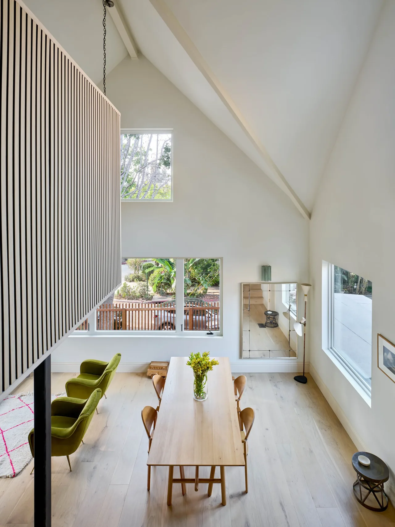 Dining room with vaulted ceiling, large windows, and mid-century modern furniture in a neutral palette.