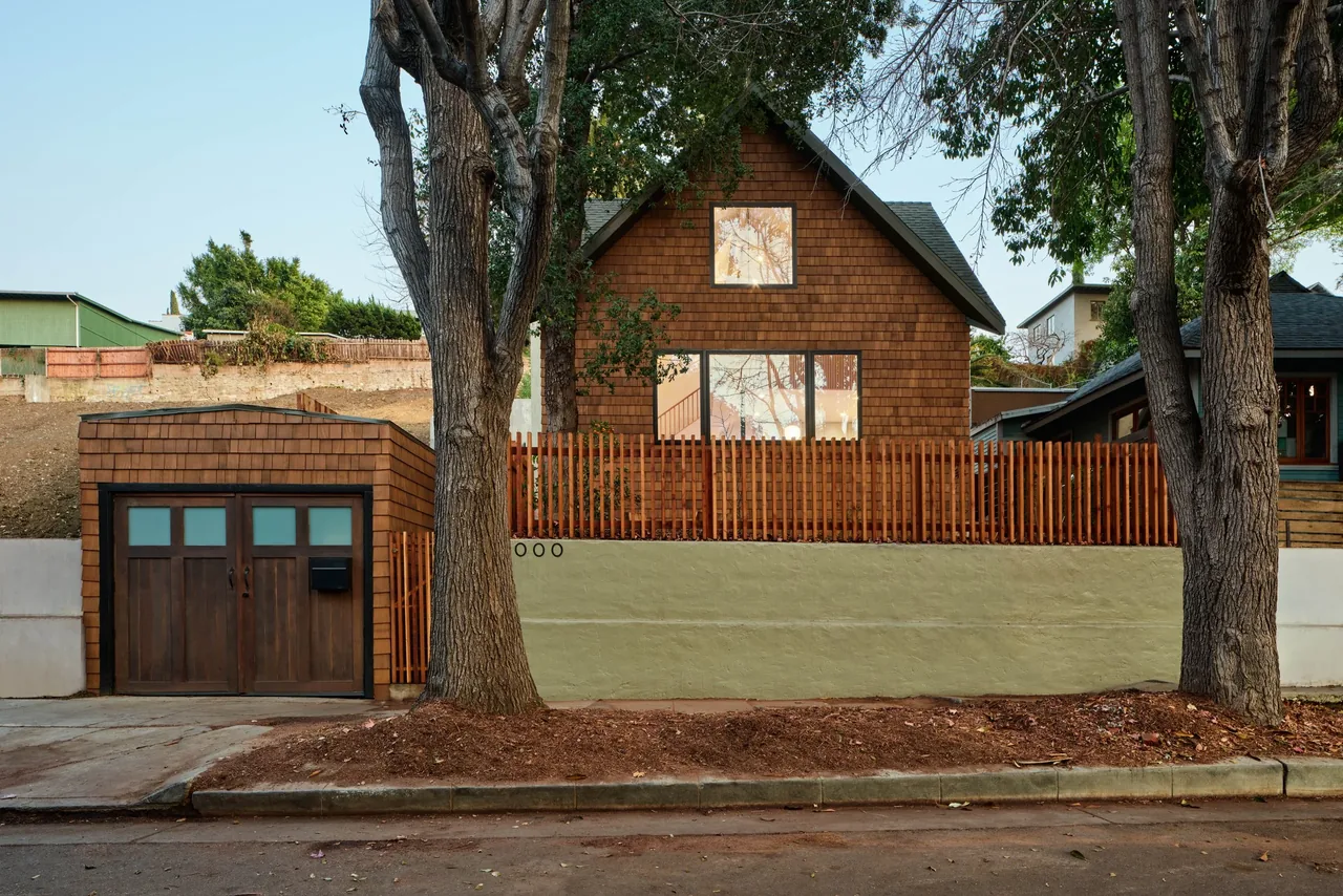 Silver Lake Treehouse features cedar shingle siding, a detached garage with wooden doors, and a vertical wooden fence along the street.