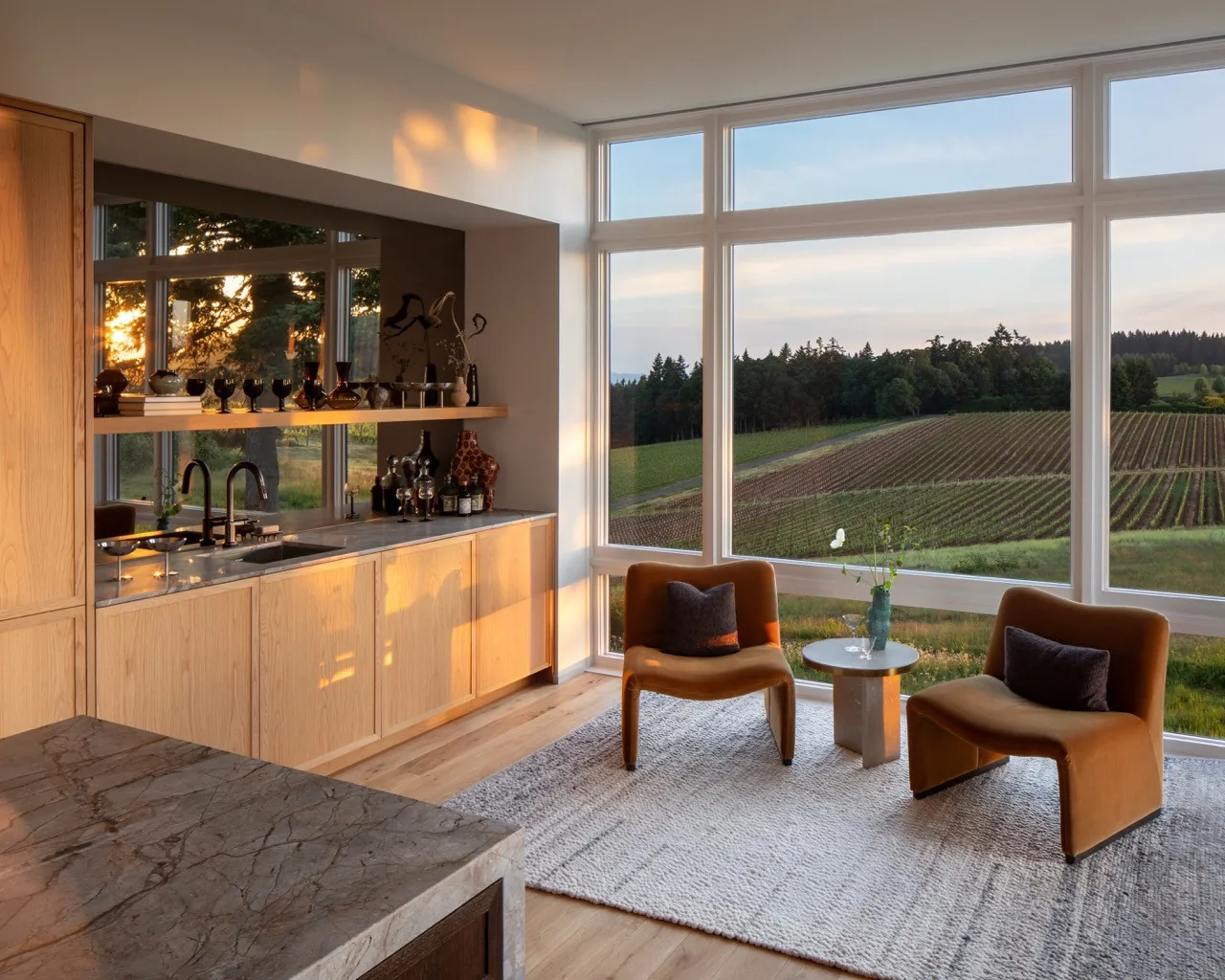 The Hillside House features a seating nook with expansive floor-to-ceiling windows framing vineyard views.
