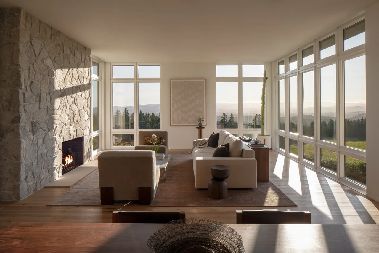 Living room of Hillside House featuring floor-to-ceiling glazing and a stone fireplace, designed with modern style.