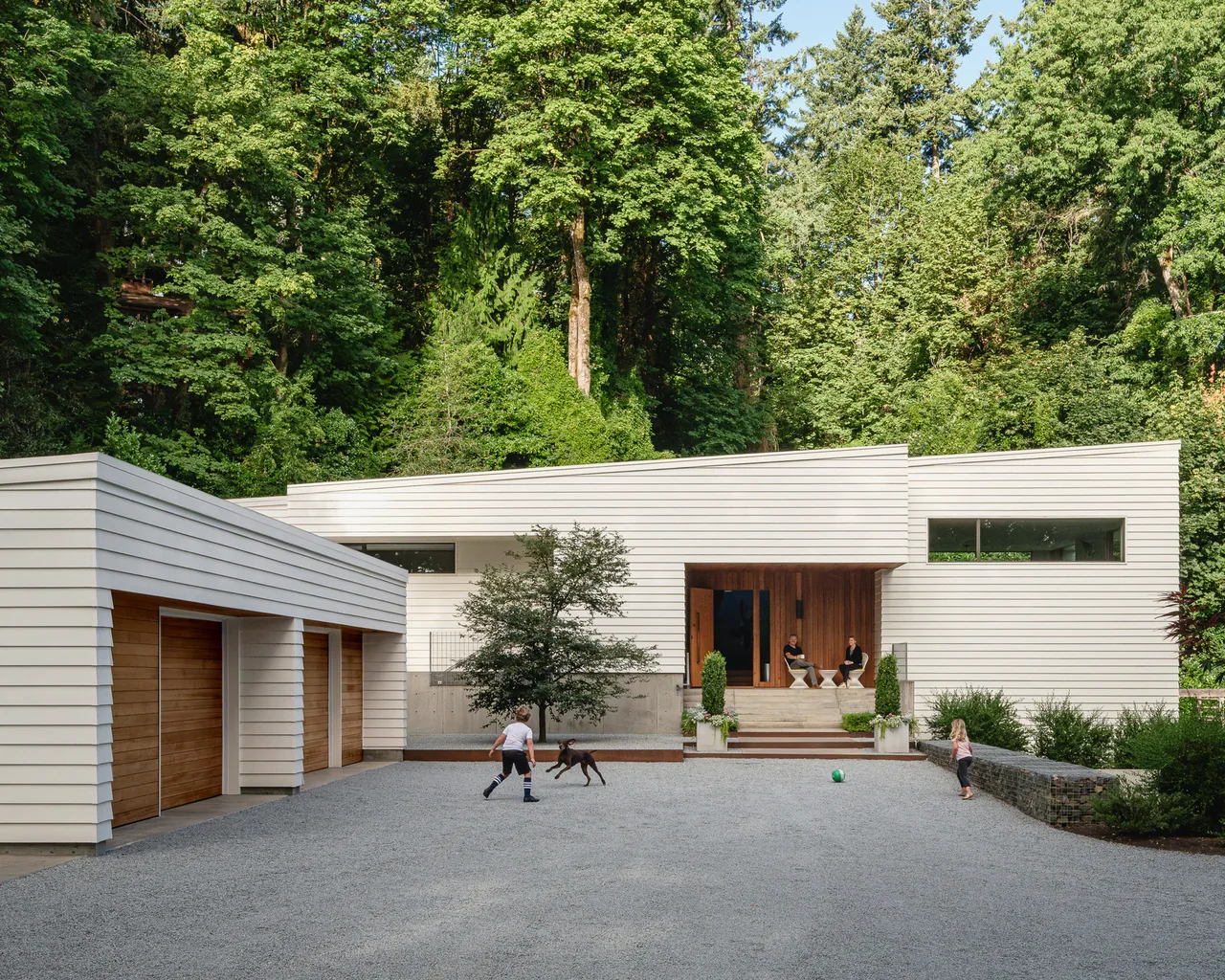 Idea House by JHL Design in Portland features a modern exterior with white siding and wood garage doors.