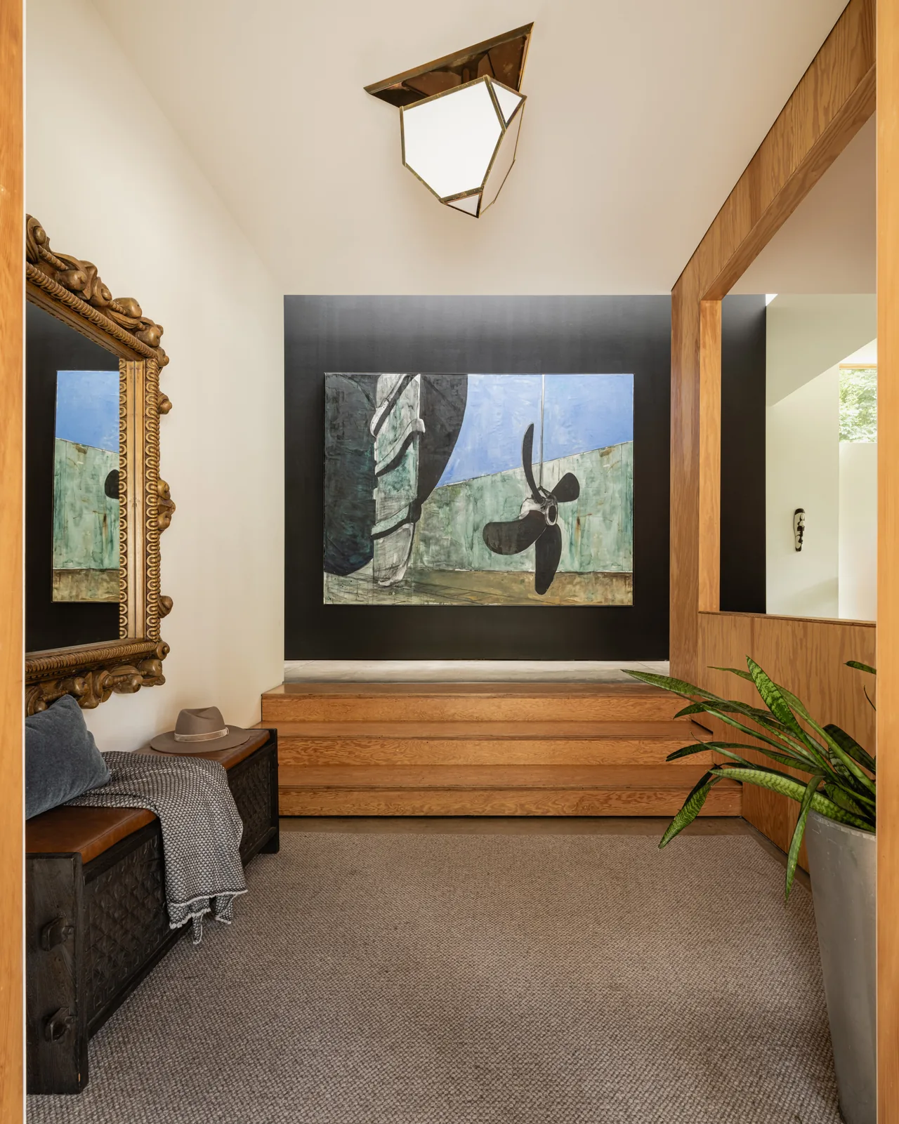 Entry hallway of the Idea House by JHL Design with wooden steps and a geometric ceiling light.