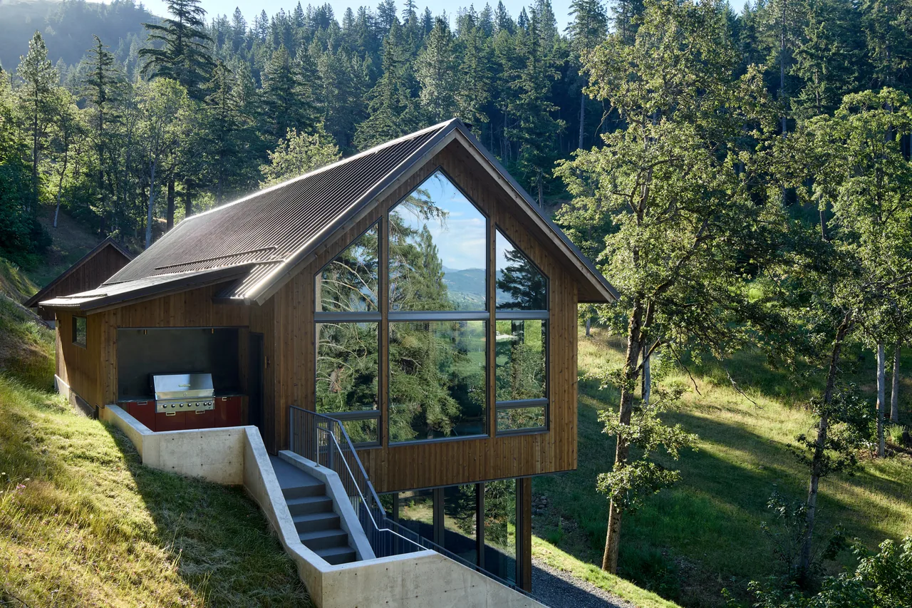 Sanford Spring features a hillside home with wood siding and a large floor-to-ceiling triangular window by JHL Design.