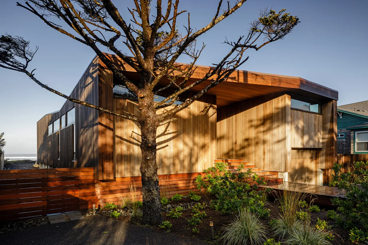Shelter House features wood-paneled walls and horizontal clerestory windows, with a landscaped yard and wooden walkway.