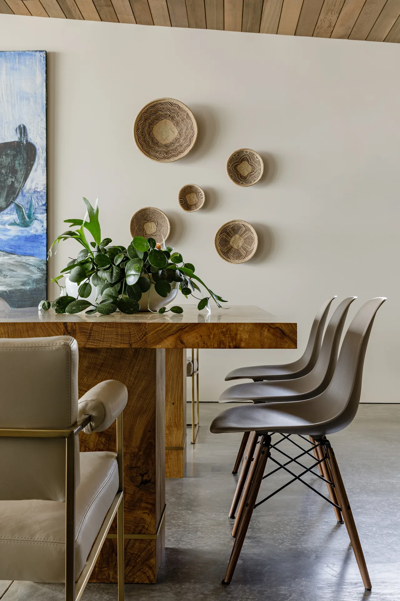 Dining space features a solid wood table, molded gray chairs, and basket wall decor under a wood-paneled ceiling.