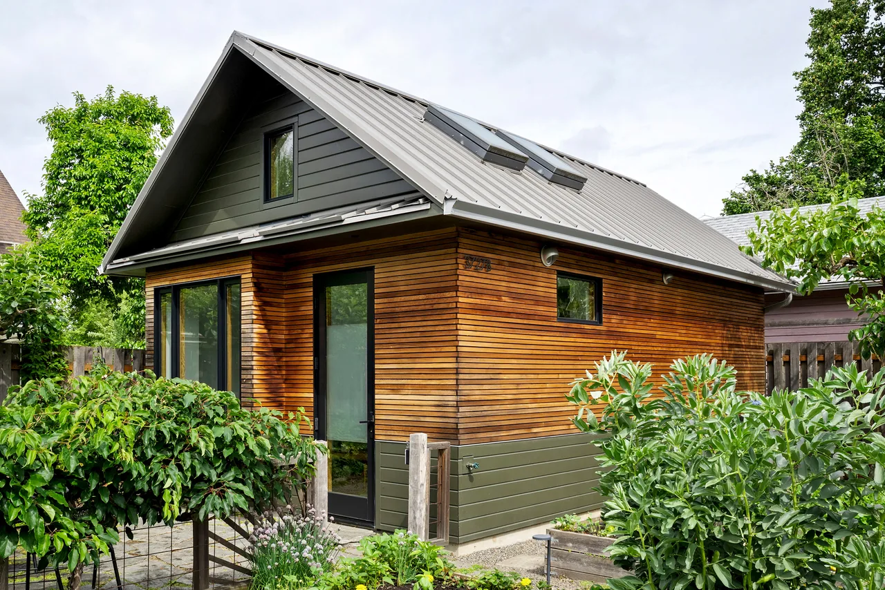 Irving Park ADU features wood siding, green paneling, and a standing seam metal roof with skylights by Tweto Architecture.