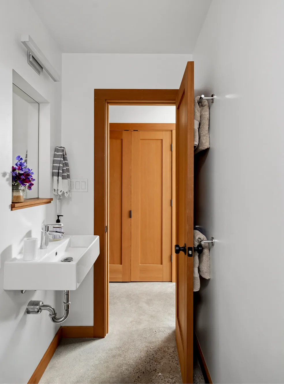 Compact bathroom with a wall-mounted sink and wooden interior door leading to a closet.