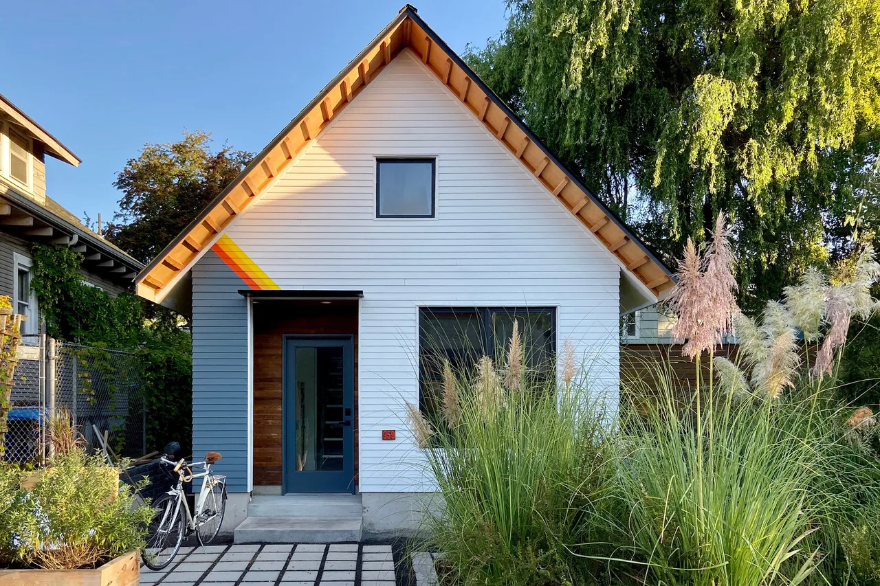 Mason Street ADU features a steep gable roof, painted wood siding, and a blue entry door with a surrounding garden.