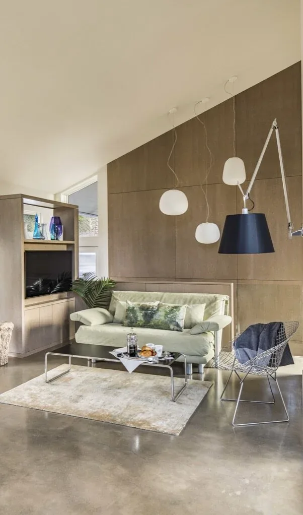 Living space features pale green sofa, wire chair, pendant lights, and polished concrete floor in Mid-century Inspired ADU.