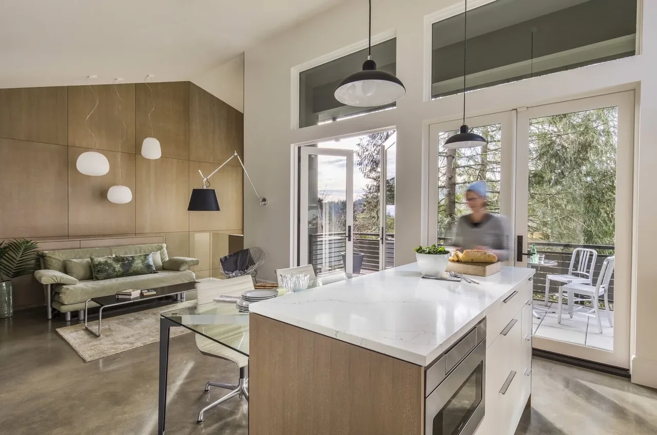 Mid-century inspired open kitchen and living space with polished concrete floor and large glass doors to balcony.