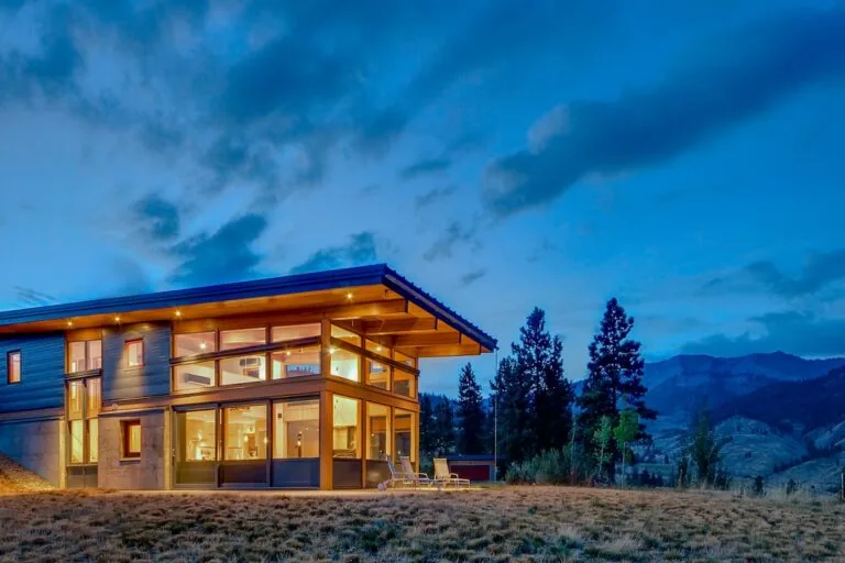 Nahahum Canyon Residence by Studio Zerbey features a wood overhang and floor-to-ceiling corner windows overlooking natural hills.