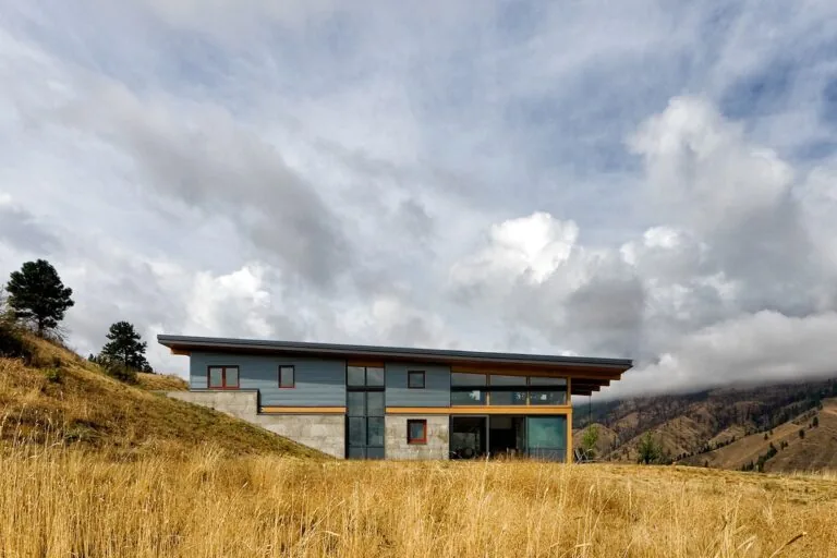 Nahahum Canyon Residence features a flat roof with a large overhang and extensive glazing facing the hillside.