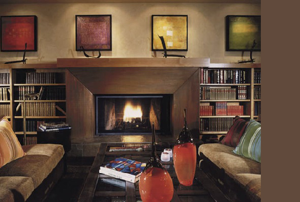 Living room featuring a central fireplace with wood surrounds, flanked by bookshelves and framed abstract art.