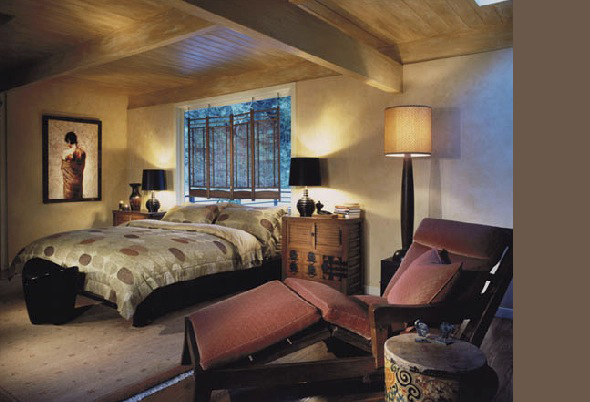 Bedroom featuring a wooden ceiling with beams, a bed with patterned bedding, and a lounge chair with a tall lamp nearby.