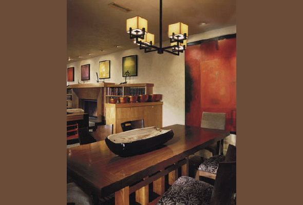 Dining room featuring a wooden table, upholstered chairs, and warm abstract wall art under pendant lighting.
